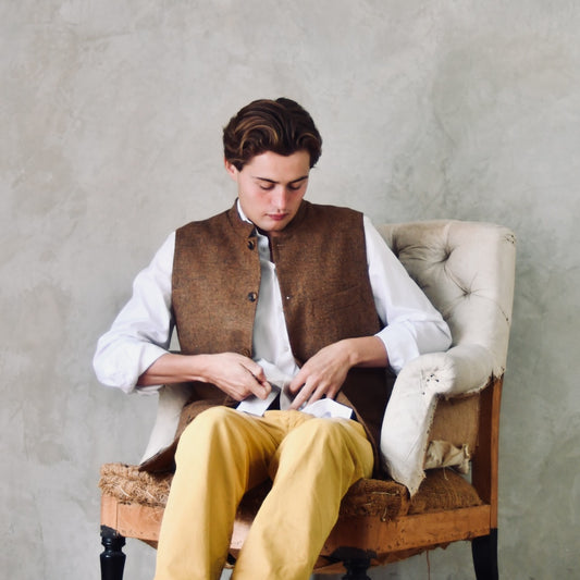 Fitted Cut Nehru Style Gilet in Brown finely woven Yorkshire tweed. Handmade in London, this gilet has five buttons to the front, a Nehru collar. three outside and two inside pockets. Smart and wearable in both Town and Country. Seated View.