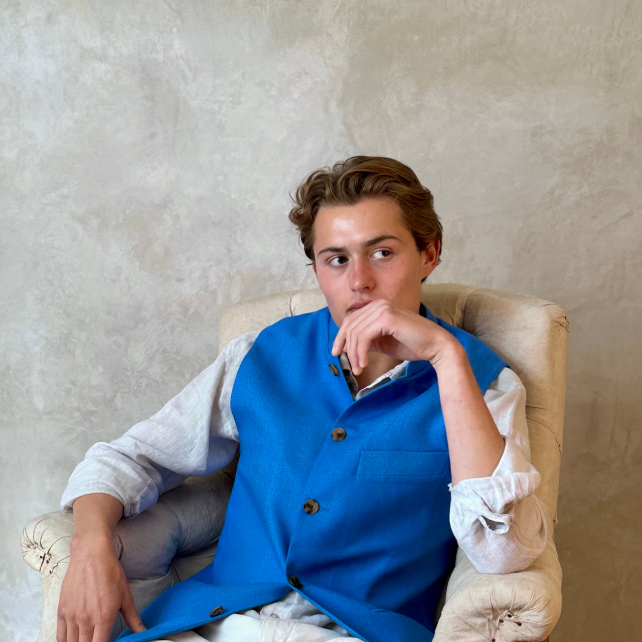 Slim fit gilet in sky blue summer weight silk weave. Handmade in London this fitted waistcoat has five pockets and a Nehru collar. Made in Great Britain. Seated Front shot.