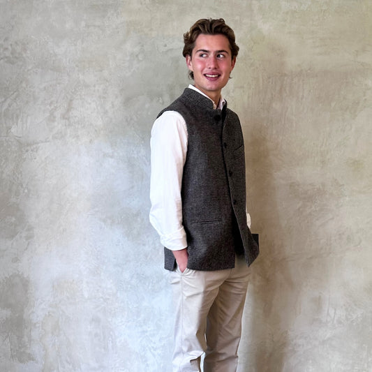 Warm Nehru Style Gilet in pure wool tweed from Hawick. Handmade in London this waistcoat has a gentle patterning in blue and shades of taupe and grey. Ample pocket space, side vents and a nead Mandarin Collar. Side View.