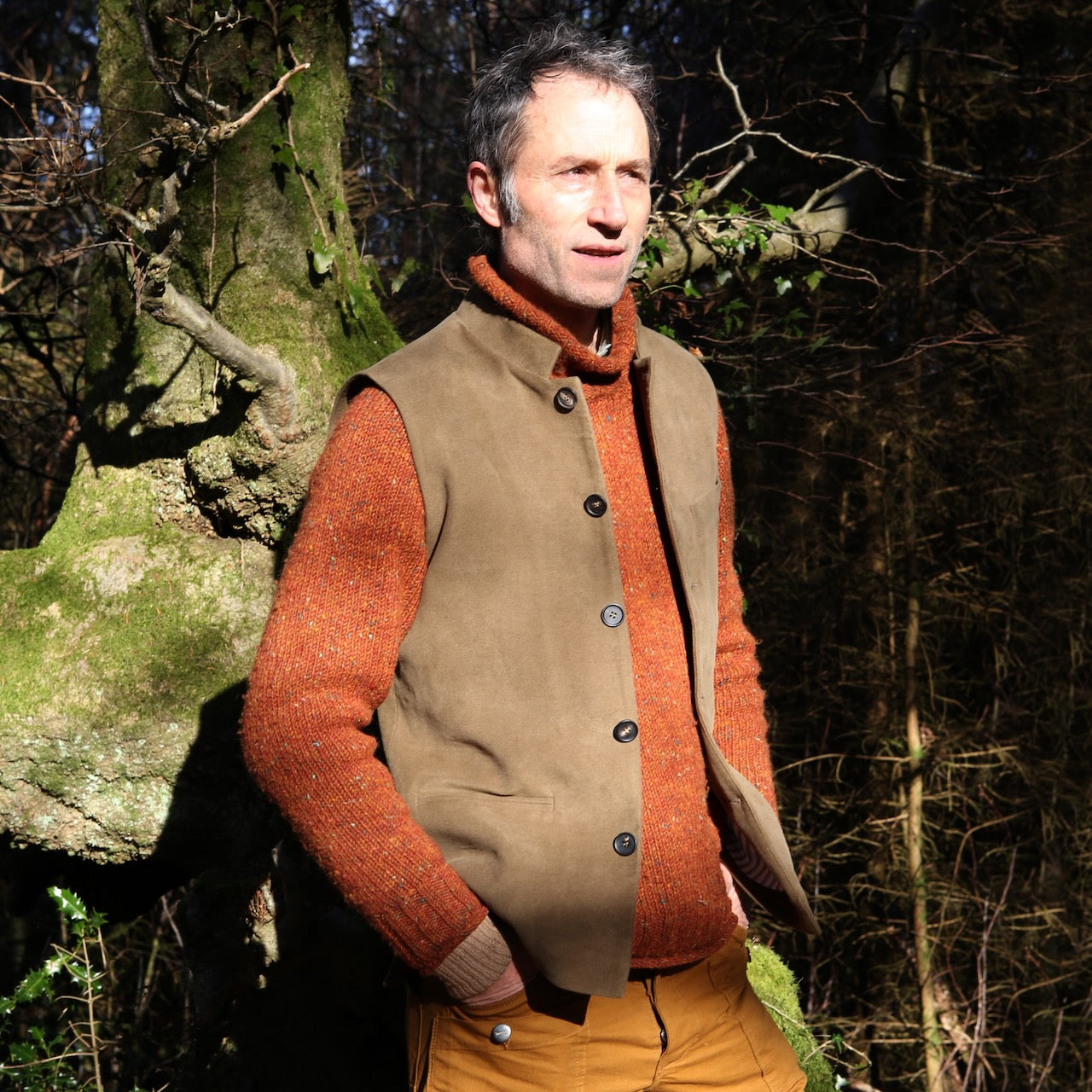 Slim Cut Nehru Style Gilet in Khaki Moleskin. This pure cotton gilet is lined in striped cotton Ticking. With a Nehru collar and five pockets it will take you everywhere and keep you warm on cooler days. Made by Hand in London. Shown worn over russet coloured jumper.