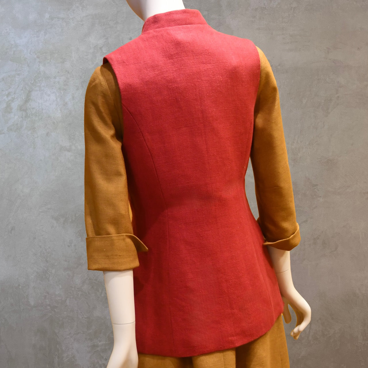 Rear Shot of Ladies Shaped Gilet in Red Irish linen. Handmade in London the waistcoat is shown worn over a mustard coloured silk dress by EdNerat.