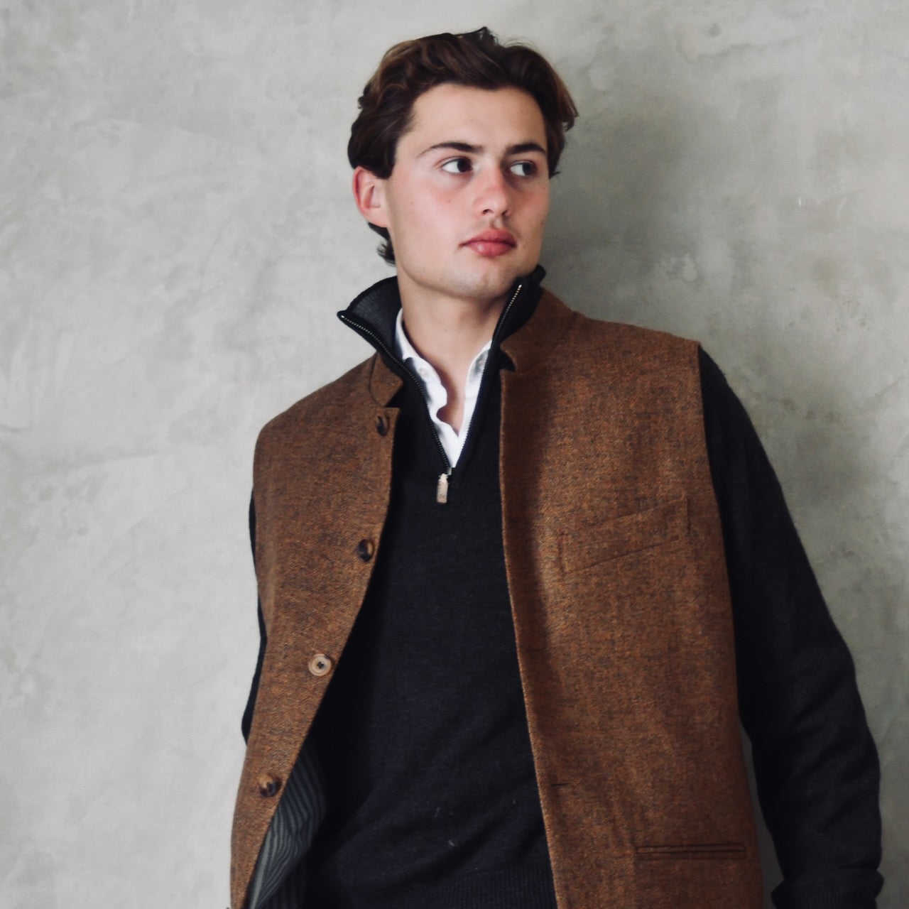 Fitted Nehru style gilet in a lovely orange brown Yorkshire tweed. Three outside and two inside pockets make this a splendid alternative to a jacket. It can be dressed up or down and the finely woven tweed will work as well in the city as in the country. Handmade in London. Worn over navy jumper.