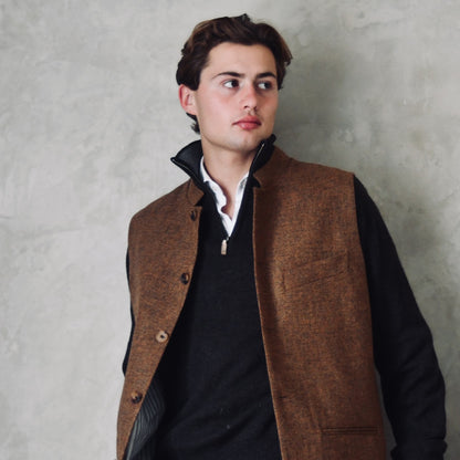 Fitted Nehru style gilet in a lovely orange brown Yorkshire tweed. Three outside and two inside pockets make this a splendid alternative to a jacket. It can be dressed up or down and the finely woven tweed will work as well in the city as in the country. Handmade in London. Worn over navy jumper.