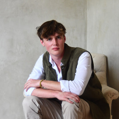 Bespoke Loose Cut Nehru Style Gilet in Khaki Cotton Corduroy. Handmade in London. Shown Over White Shirt, Seated.