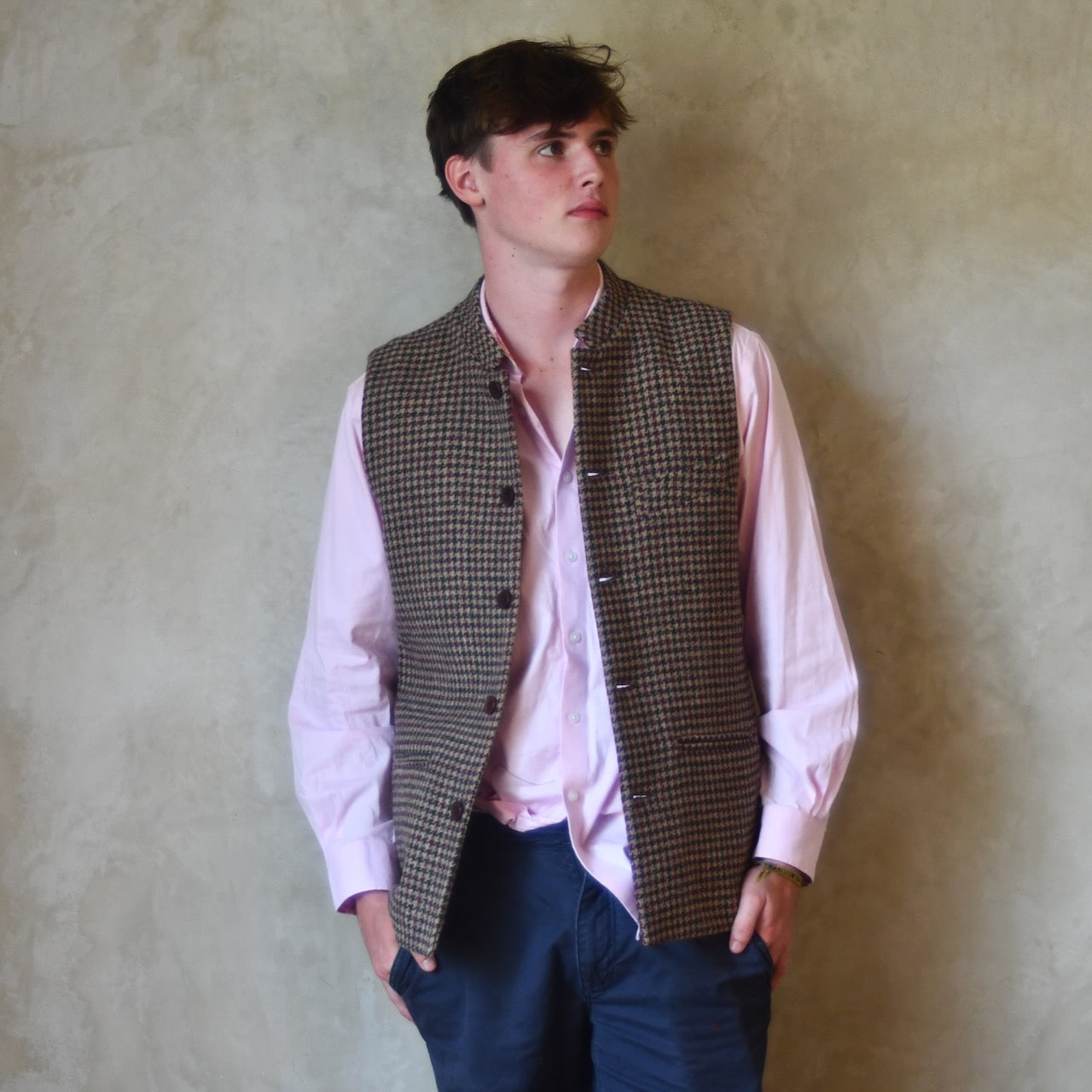 Unbuttoned casual shot of Slim Cut Nehru Style  Gilet in checked pure wool tweed from Lovat Mill. Handmade in London. Worn over pink shirt.