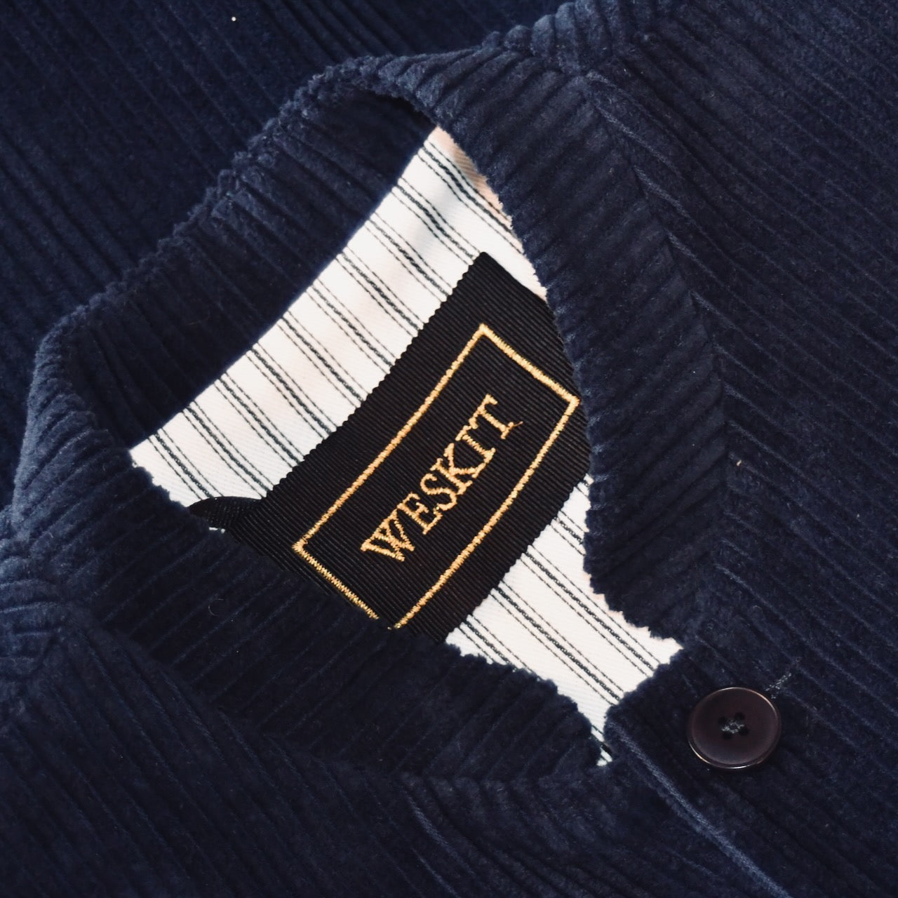 Collar detail on dark navy cotton corduroy waistcoat showing ticking lining, embroidered label and Mandarin collar.