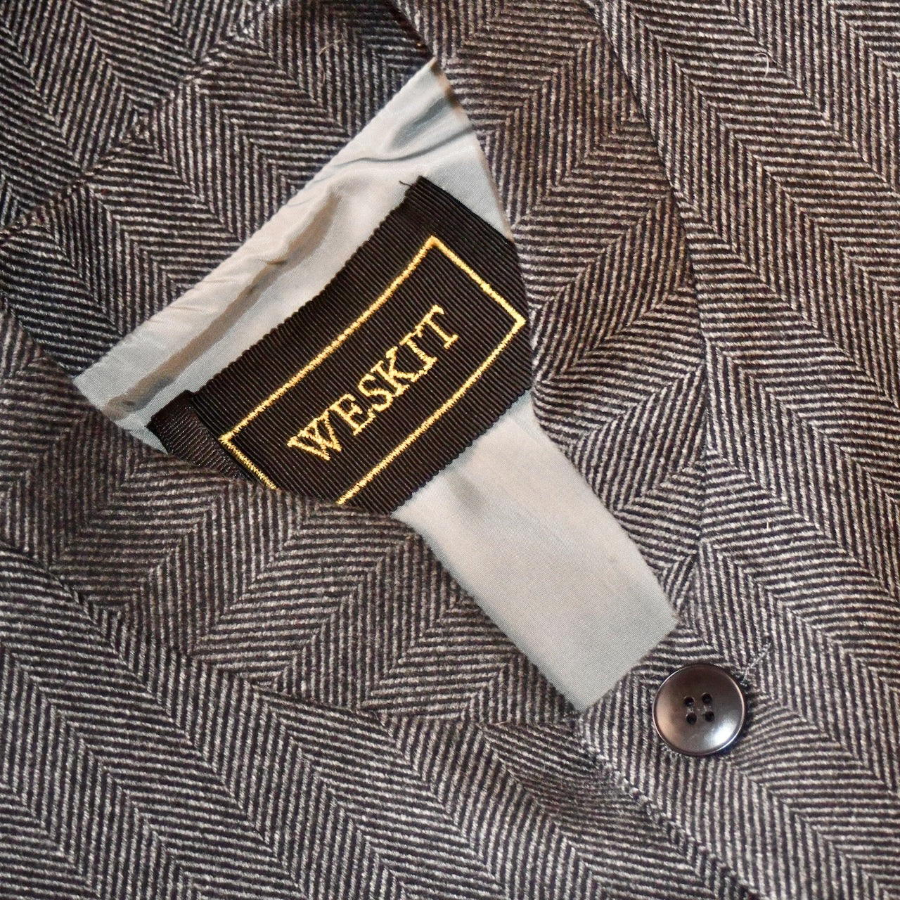 Charcoal Merino Flannel Gilet showing embroidered label and Light Grey Viscose Lining. Handmade in Britain.