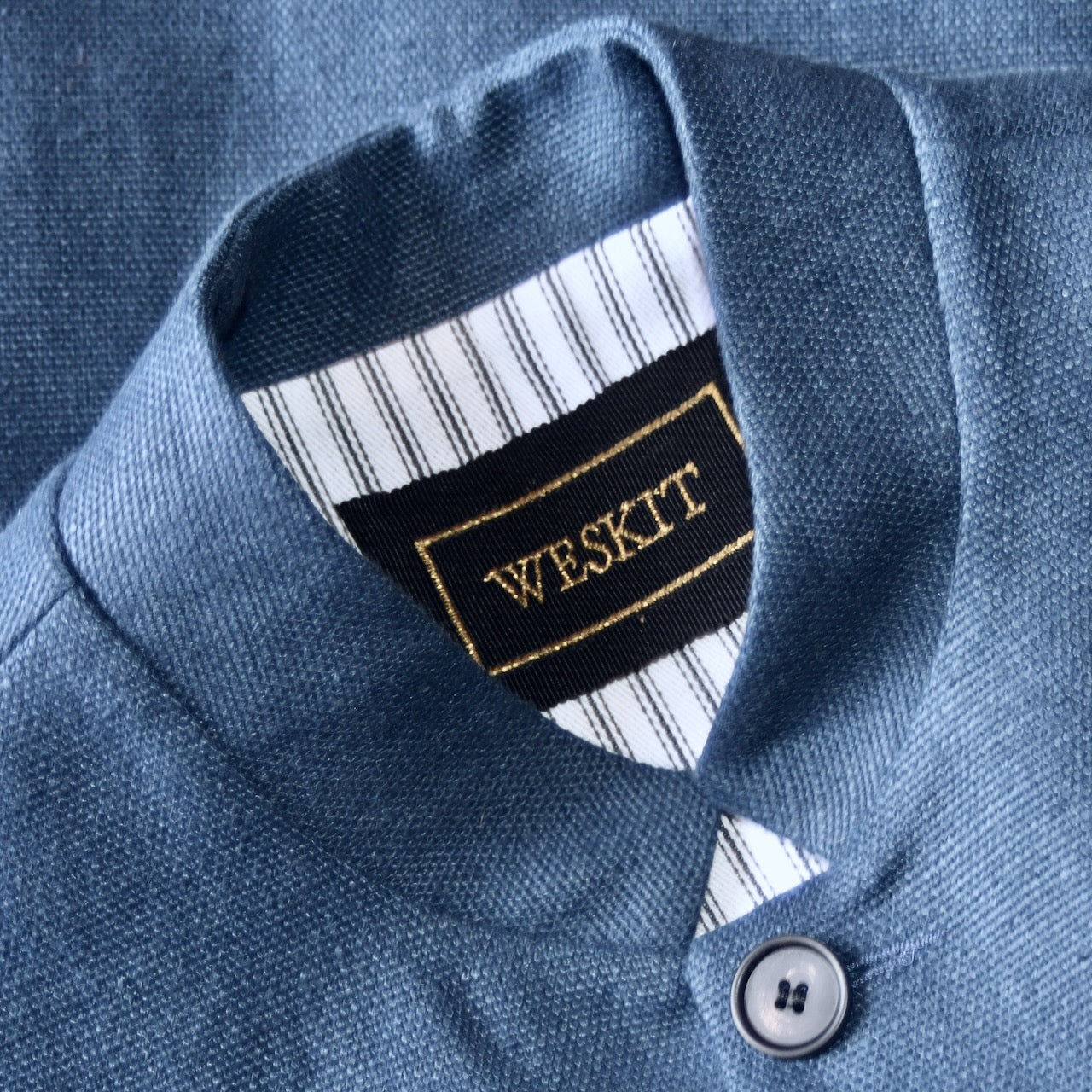 Nehru Style Gilet in Heavy Blue Linen. Irish Linen Gilet, Made by Hand in London. Entirely made in Great Britain. Close up on Nehru Collar showing Striped Cotton Ticking Linen and embroidered label on black ribbed silk.