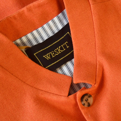 Close up on Nehru Collar of Slim fit nehru style gilet in summer weight silk weave fabric. Handmade in London, this orange silk matka fitted waistcoat has a Nehru collar, Courtney & Co buttons and is fully lined in striped cotton ticking. 