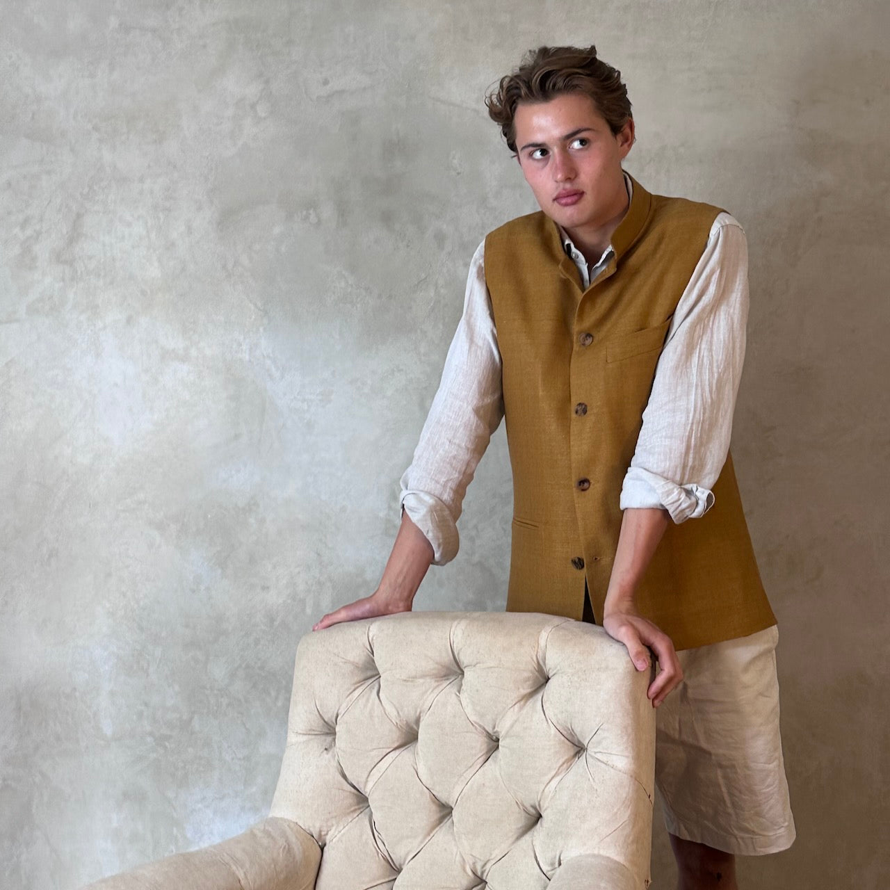 Tan coloured slim fit gilet in a summer weight silk weave. Handmade in London this fitted waistcoat has five pockets and a Nehru collar. Made in Great Britain. Standing side shot.