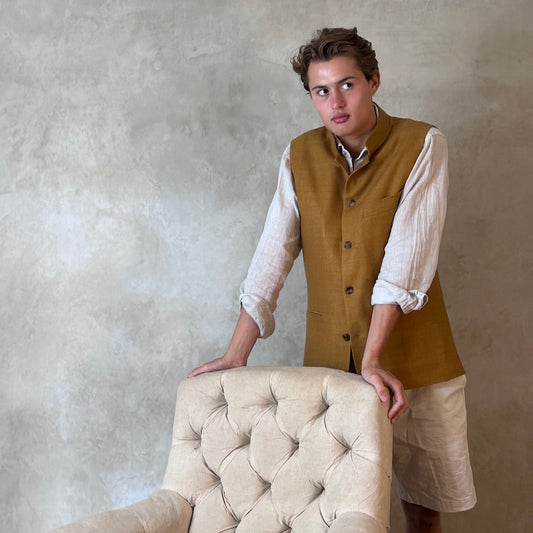 Tan coloured slim fit gilet in a summer weight silk weave. Handmade in London this fitted waistcoat has five pockets and a Nehru collar. Made in Great Britain. Standing side shot.