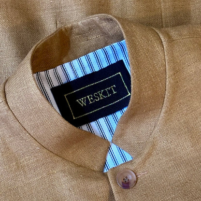The perfect alternative to a jacket on hotter days, this summer weight slim fit gilet is handmade in London. Made up in a pure silk matka, the waistcoat is fitted and fully lined with two inside and three outside pockets. Close up shot showing gNehru collar, silk embroidered label and striped cotton ticking lining.