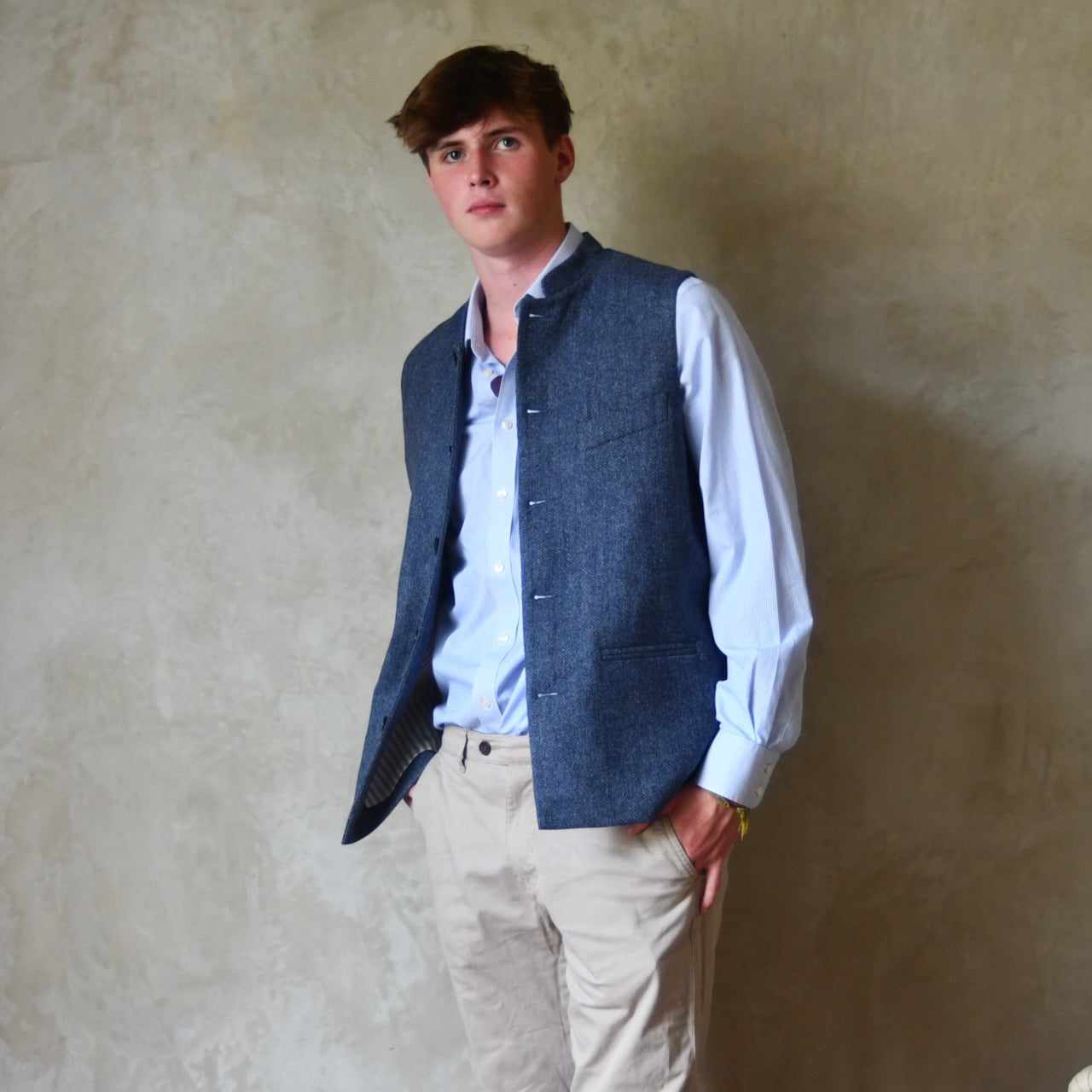 Loose Fit Nehru Style Gile in Demin Blue Herringbone Tweed. Handmade in London to order. Bespoke Sizing available. Full shot showing the Gilet unbuttoned over white shirt and blue trousers.