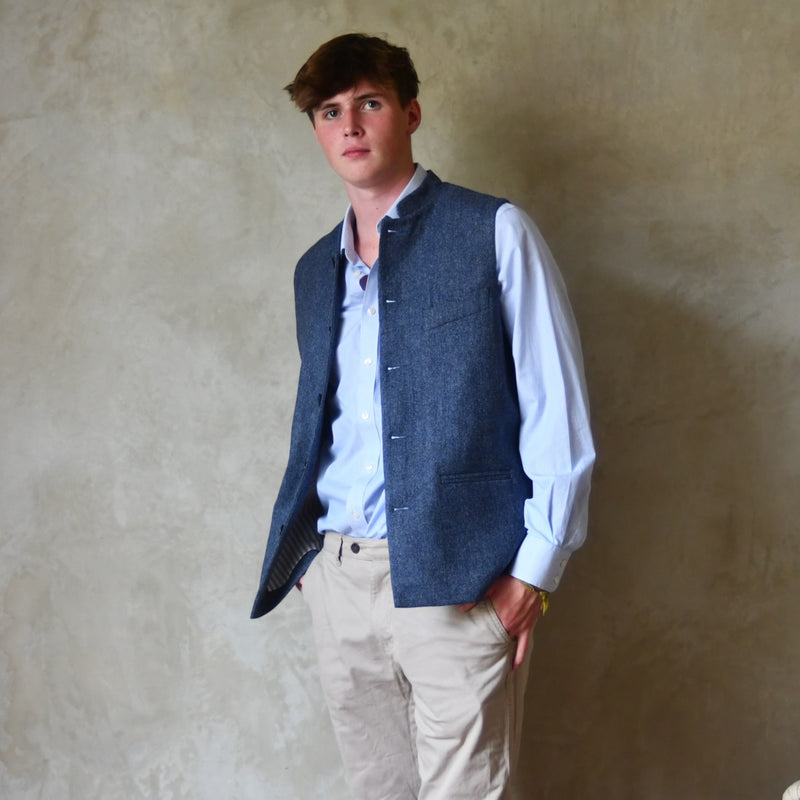 Loose Fit Nehru Style Gile in Demin Blue Herringbone Tweed. Handmade in London to order. Bespoke Sizing available. Full shot showing the Gilet unbuttoned over white shirt and blue trousers.