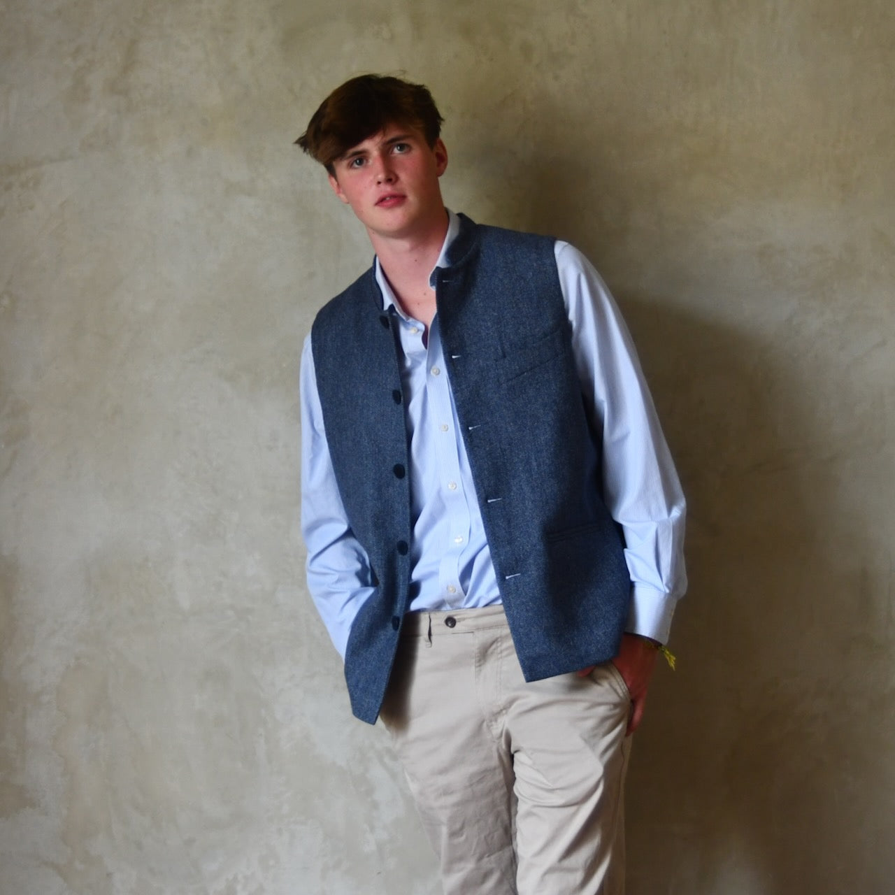 Loose Fit Nehru Style Gile in Demin Blue Herringbone Tweed. Handmade in London to order. Bespoke Sizing available. Shown unbuttoned over blue shirt and blue trousers.