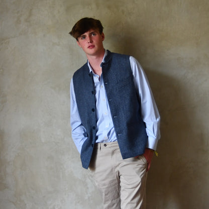 Loose Fit Nehru Style Gile in Demin Blue Herringbone Tweed. Handmade in London to order. Bespoke Sizing available. Shown unbuttoned over blue shirt and blue trousers.