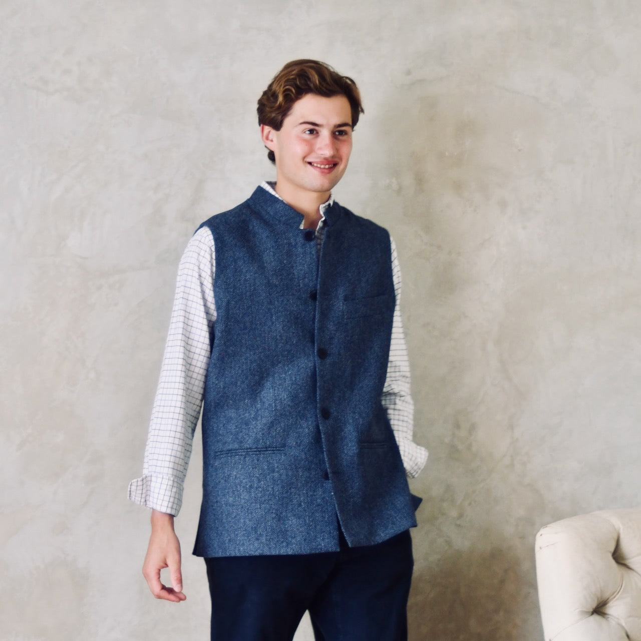 Fitted Cut Nehru-Style Gilet in Denim Blue Herringbone Tweed. A Tailored Cut waistcoat in magical mid-to-warmer weight lambswool tweed with a herringbone patterning.
Giving the overall effect of a delightful denim from a distance, this textiles brightens up on closer inspection as the depths and vivid colours of its patterning are revealed.
Smart, elegant and urbane – but as easy to match with jeans as it is to wear more formally.