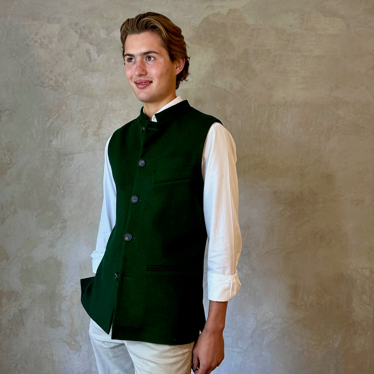 Slim Cut Nehru Style Gilet in bottle or British racing green pure merino flannel. This pure wool gilet is hand made in London. The thick merino wool flannel is woven in Yorkshire by AW Hainsworth. A perfect Town-to-Country dressing solution. Side View.