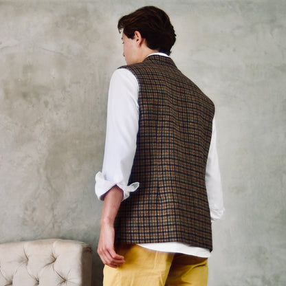 A superbly fine tweed that Nehru Style Gilet. Worth every penny, it will take you everywhere, smartly. A smokey brown and dull green weave a stunning check against a warm hued background, creating an unusual and bold check that will hold its own anywhere. Woven in Somerset, Cu. Made and Finished in London, this Gilet is entirely made in Great Britain. Back shot showing rear darts.