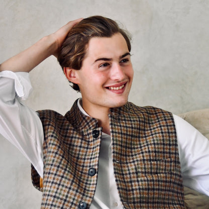 A superbly fine tweed that Nehru Style Gilet. Worth every penny, it will take you everywhere, smartly. A smokey brown and dull green weave a stunning check against a warm hued background, creating an unusual and bold check that will hold its own anywhere. Woven in Somerset, Cu. Made and Finished in London, this Gilet is entirely made in Great Britain.
