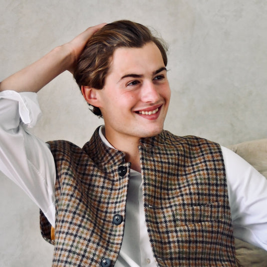 A superbly fine tweed that Nehru Style Gilet. Worth every penny, it will take you everywhere, smartly. A smokey brown and dull green weave a stunning check against a warm hued background, creating an unusual and bold check that will hold its own anywhere. Woven in Somerset, Cu. Made and Finished in London, this Gilet is entirely made in Great Britain.