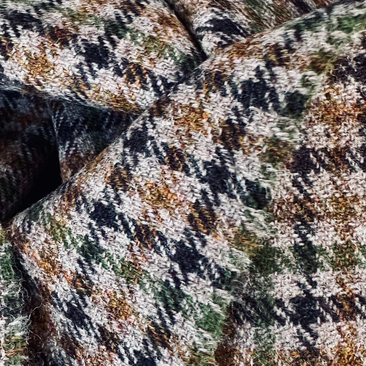 A superbly fine tweed that Nehru Style Gilet. Worth every penny, it will take you everywhere, smartly. A smokey brown and dull green weave a stunning check against a warm hued background, creating an unusual and bold check that will hold its own anywhere. Woven in Somerset, Cu. Made and Finished in London, this Gilet is entirely made in Great Britain. Fabric Close Up.