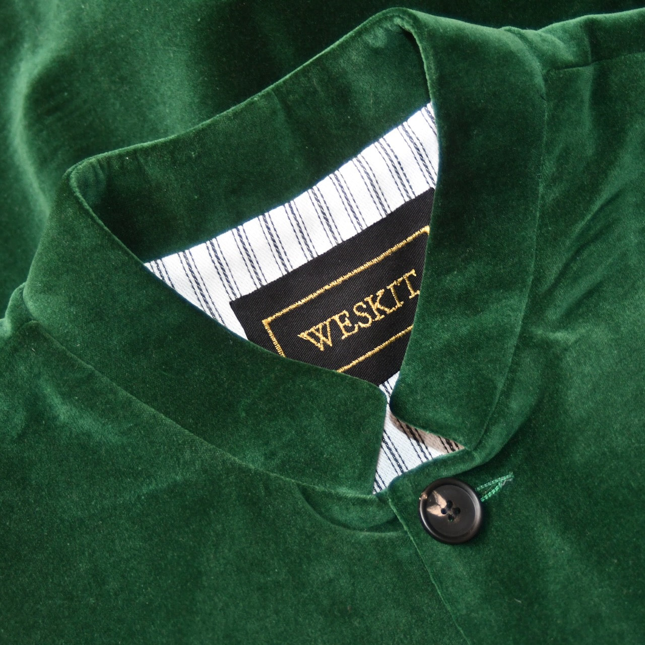 Detailed collar shot of Bottle Green Velvet Nehru-Style Gilet showing ticking lining and embroidered label.
Handmade in London.
Entirely made in Great Britain.