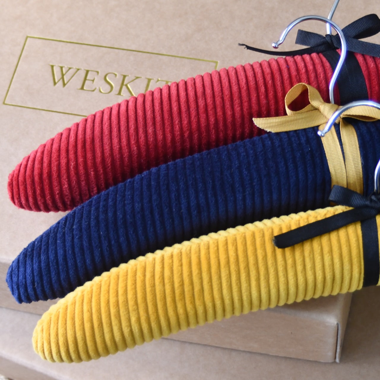 Red, Navy and Ochre Corduroy shown on Handmade Padded hangers made out of the cut-offs from Weskit Gilets and used as zero-waste swatchbook. Entirely made in Great Britain.