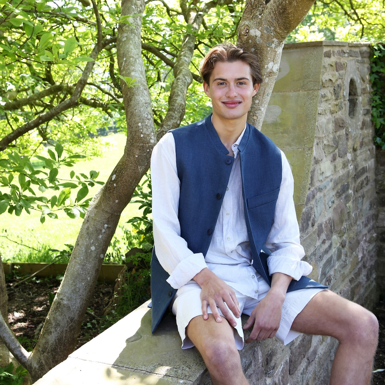 Nehru Style Gilet in Heavy Blue Linen. Irish Linen Gilet, Made by Hand in London. Entirely made in Great Britain. Seated Relaxed Exterior View.