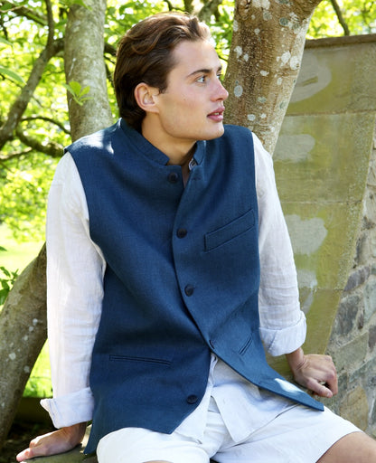 Nehru Style Gilet in Heavy Blue Linen. Irish Linen Gilet, Made by Hand in London. Entirely made in Great Britain. Seated Laid Back View.