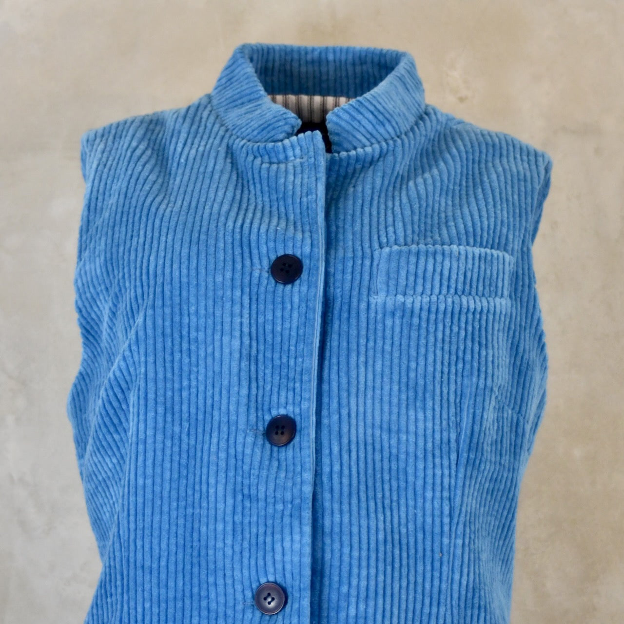 Close Up view of Blue Cotton Corduroy Ladies Waistcoat. 
Handmade in London this longer length Gilet has a Nehru collar and bllue corozo buttons.