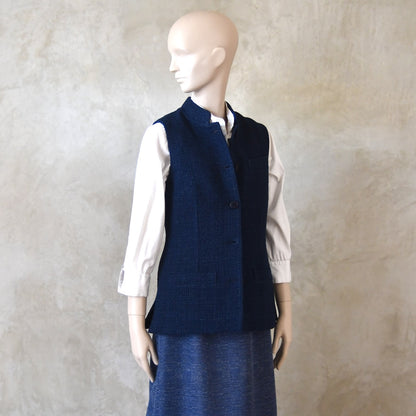 Angled Side Shot of Ladies Shaped Gilet in Linton Tweeds boucle. A deep navy spring-summer weight fabric, this gilet packs superbly and can be worn everywhere. Handmade in London.  Buttoned view.