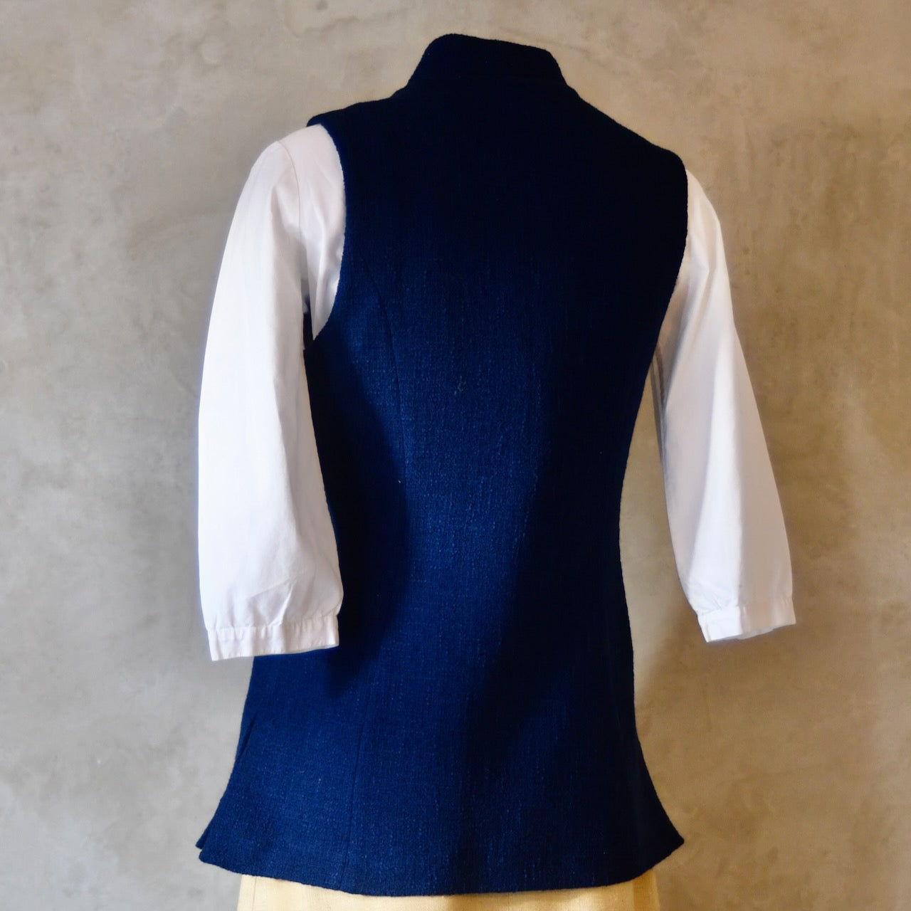 Side rear shot of Navy Ladies' Waistcoat in Linton Tweeds Boucle. This pure cotton boucle has a lightweight feel and a gentle handle. Perfect for spring, autumn and cooler summer days. Handmade in London.