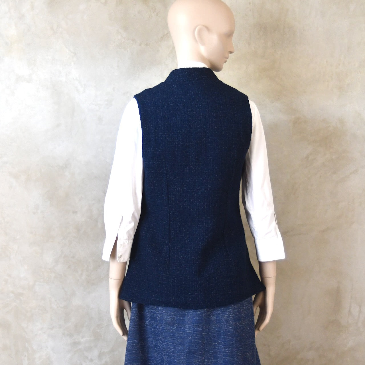 Back Shot of Ladies Shaped Gilet in Linton Tweeds boucle. A deep navy spring-summer weight fabric, this gilet packs superbly and can be worn everywhere. Handmade in London. 