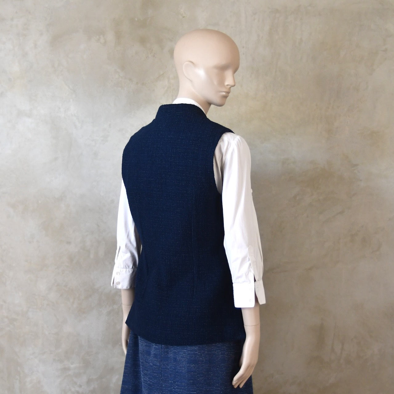 Angled Back Shot of Ladies Shaped Gilet in Linton Tweeds boucle. A deep navy spring-summer weight fabric, this gilet packs superbly and can be worn everywhere. Handmade in London. 