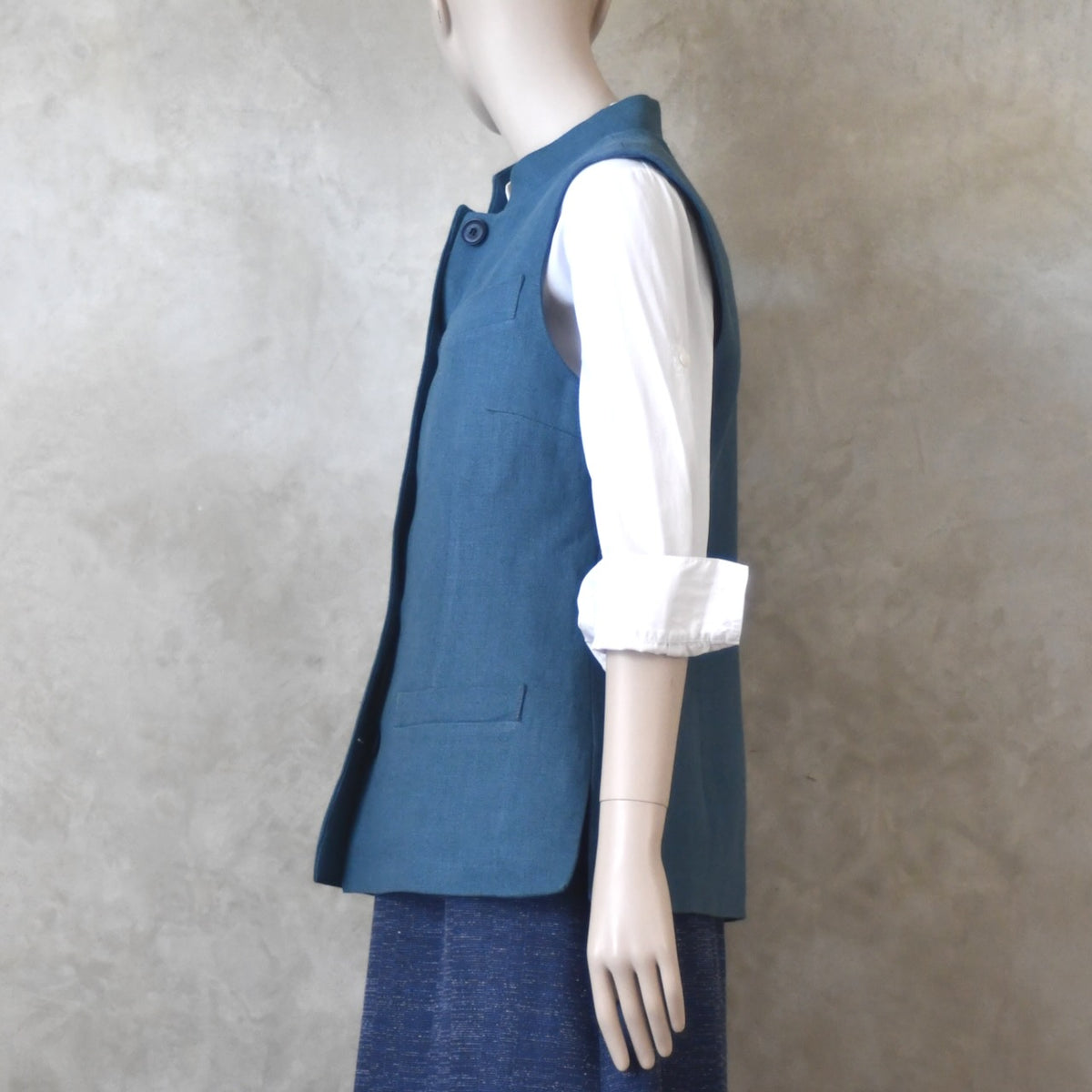 Side on shot of Ladies Gilet in Light Blue Irish Linen. Handmade in London this waistcoat has a Nehru collar, cotton ticking lining, bust darts as well as front and rear waist-shaping darts.