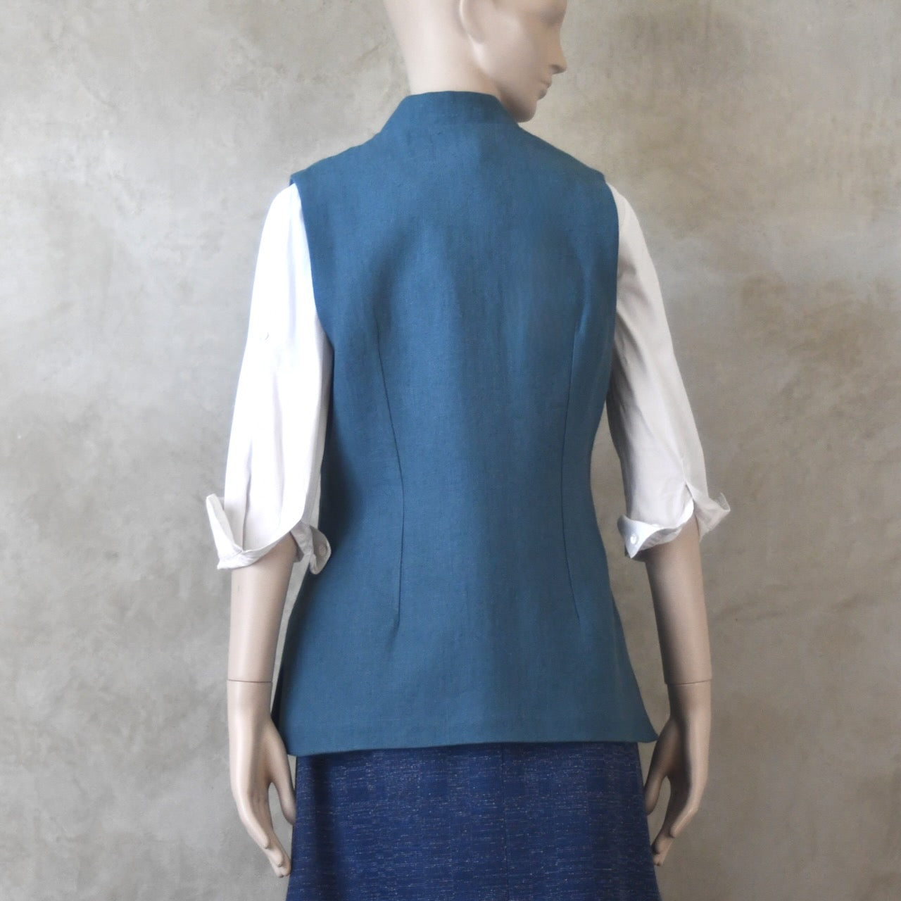 Back View of Ladies Gilet in Light Blue Irish Linen. Handmade in London this waistcoat has a Nehru collar, cotton ticking lining, bust darts as well as front and rear waist-shaping darts.