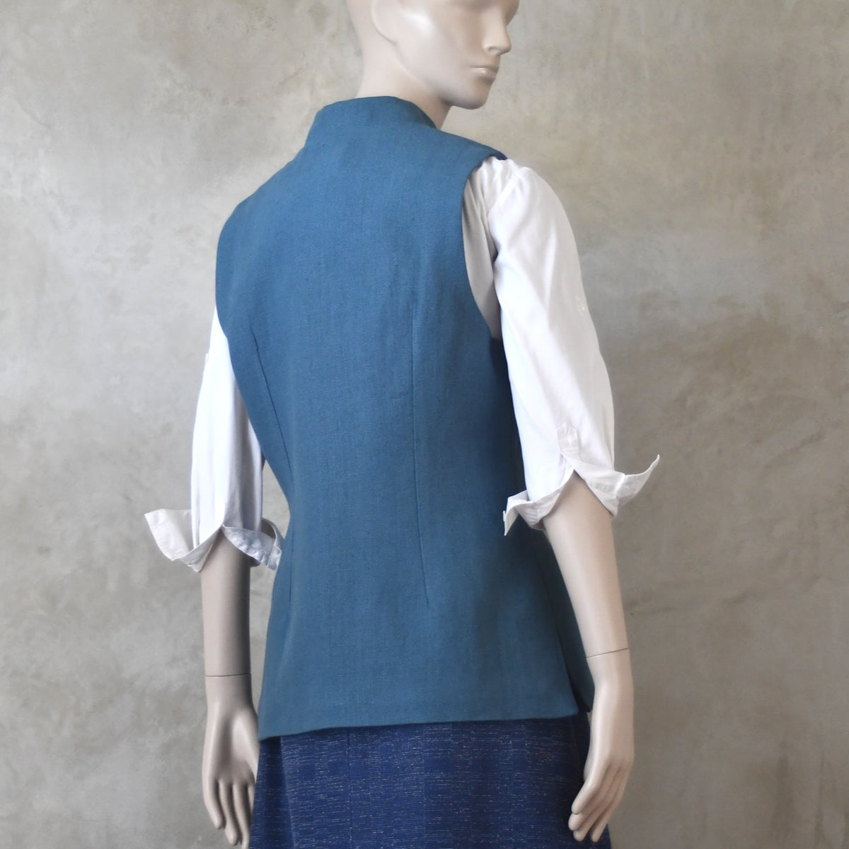 Back side view of Ladies Gilet in Light Blue Irish Linen. Handmade in London this waistcoat has a Nehru collar, cotton ticking lining, bust darts as well as front and rear waist-shaping darts.