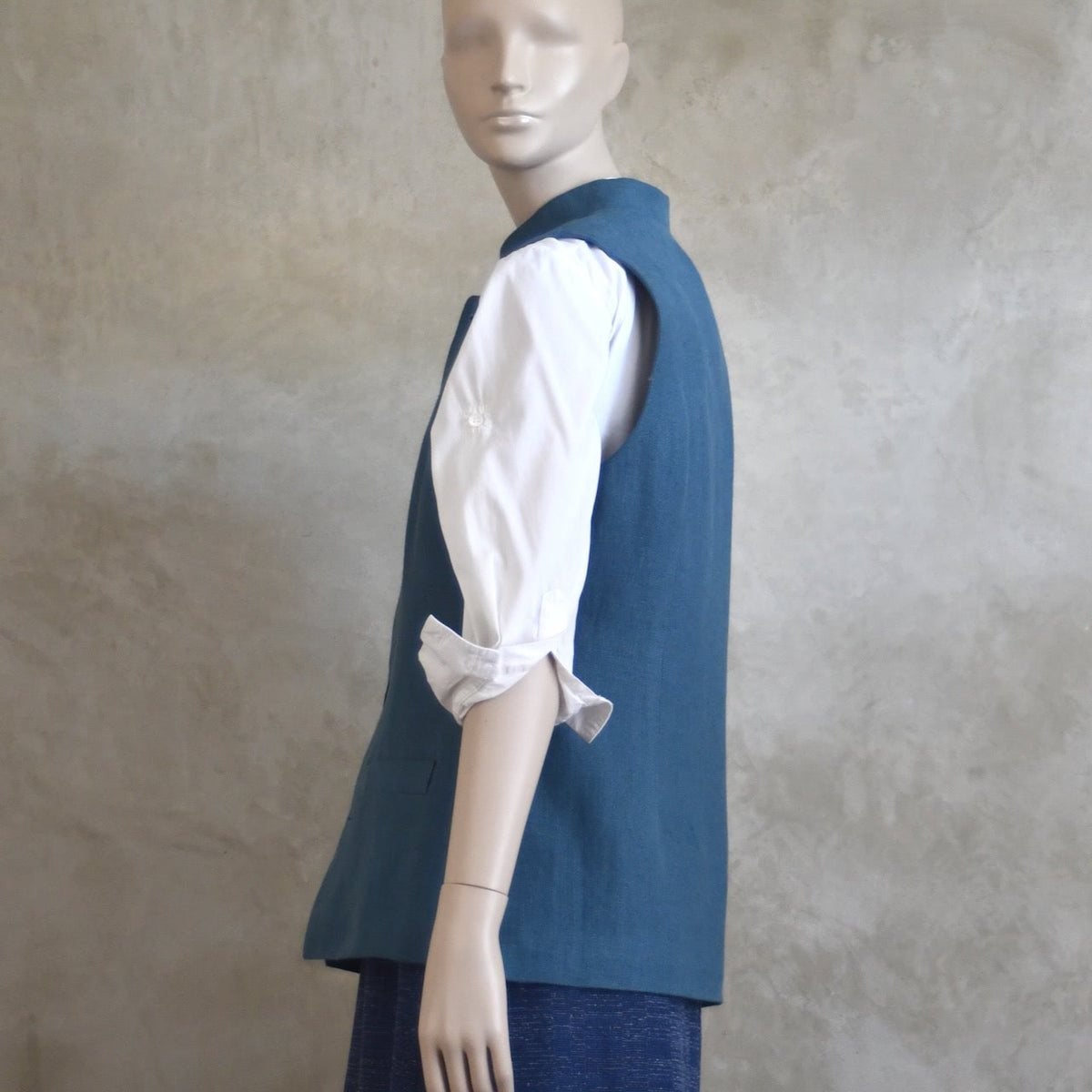Side on shot of Ladies Gilet in Light Blue Irish Linen. Handmade in London this waistcoat has a Nehru collar, cotton ticking lining, bust darts as well as front and rear waist-shaping darts.