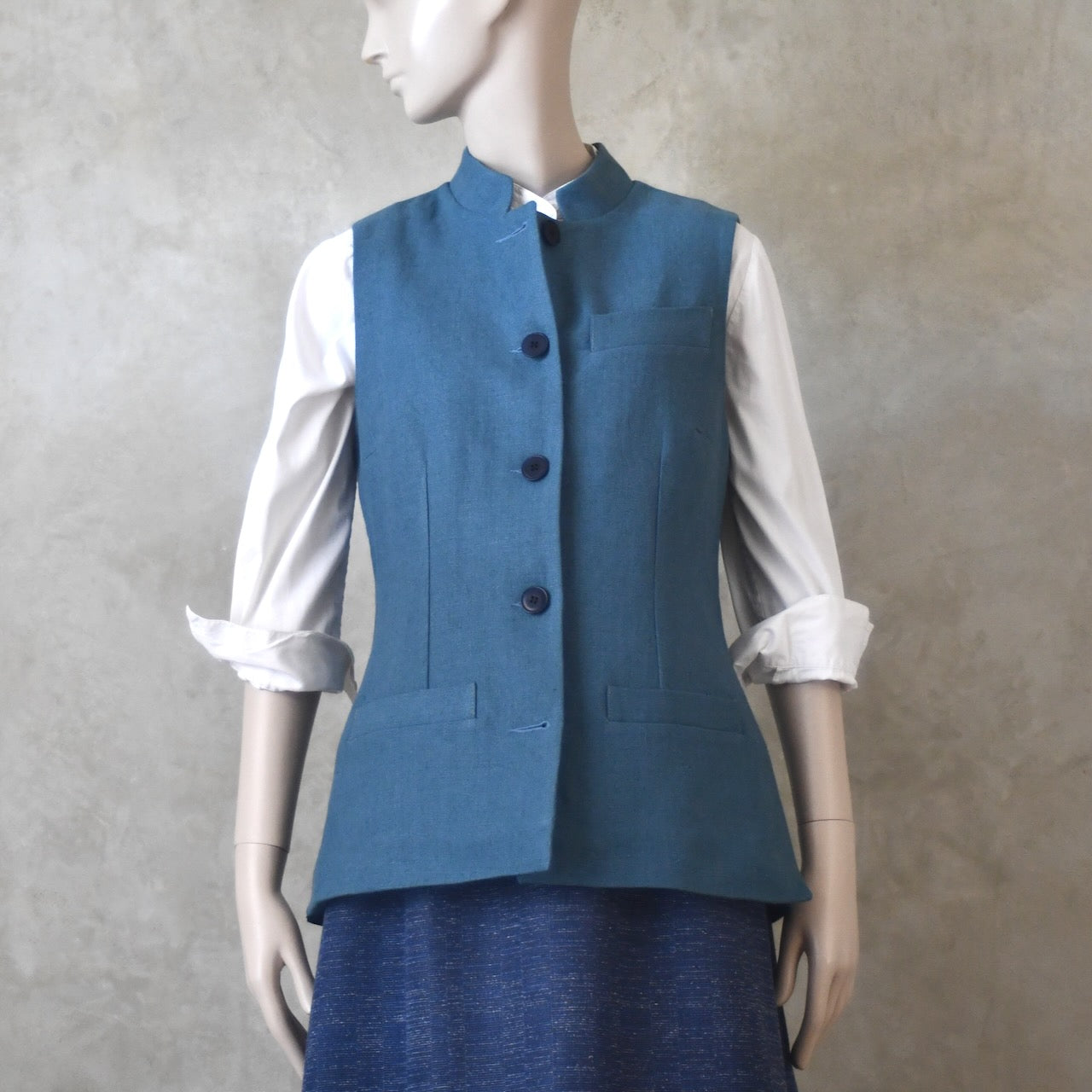 Buttoned front shot of Ladies Gilet in Light Blue Irish Linen. Handmade in London this waistcoat has a Nehru collar, cotton ticking lining, bust darts as well as front and rear waist-shaping darts.