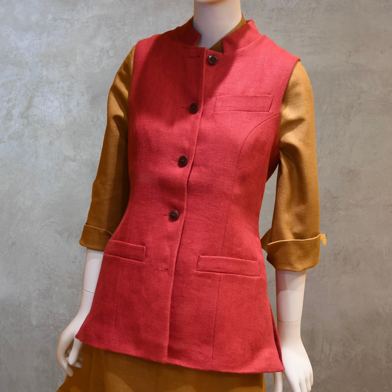 Angled Front Shot of Ladies Shaped Gilet in Red Irish linen. Handmade in London the waistcoat is shown worn over a mustard coloured silk dress by EdNerat.