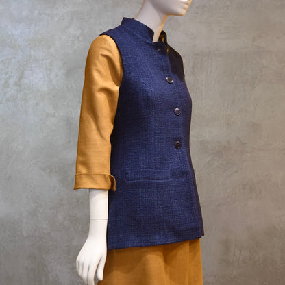Longer Length Ladies Waistcoat in Linton Tweeds Boucle. A pure cotton weave,  this is superbly trans-seasonal option. Handmade in London. Side Shot shown over mustard coloured Silk Matka Dress from Ednerat.