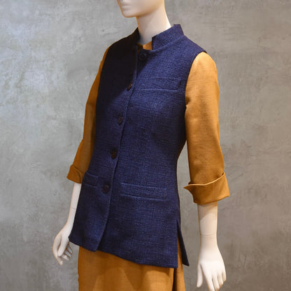 Longer Length Ladies Waistcoat in Linton Tweeds Boucle. A pure cotton weave,  this is superbly trans-seasonal option. Handmade in London. Side on Shot shown over mustard coloured Silk Matka Dress from Ednerat.
