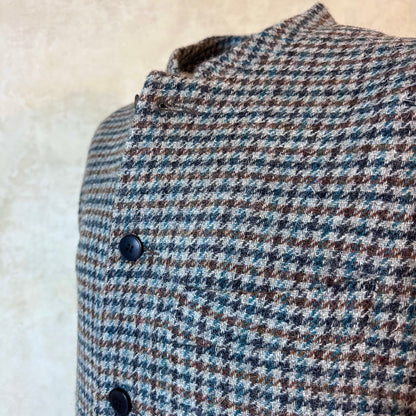 Fabric Close up on Slim Cut Nehru Style Gilet in Mist Check Lovat Tweed. This waistcoat is made up in a wonderful cross pattern of dark blue-black, brown and teal over a misty grey. Woven by Lovat Mill this is an incredibly warm and well-made tweed. Cut Made and Finished by Hand in London. Entirely made in Great Britain.