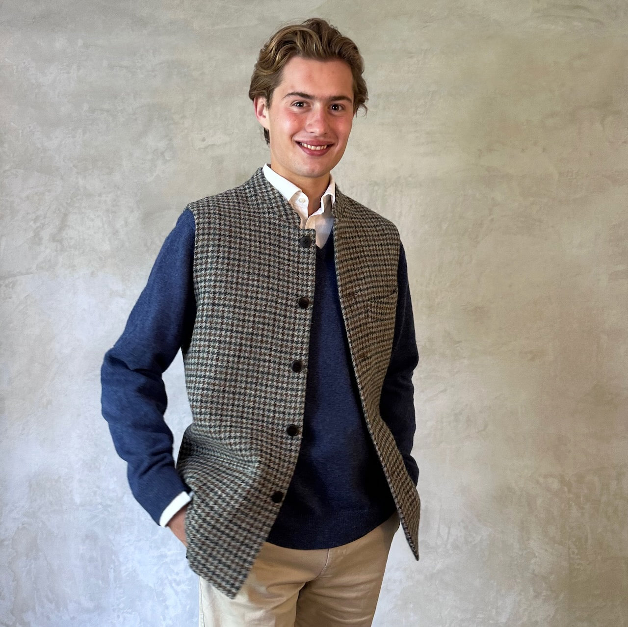 Slim Cut Nehru Style Gilet in Mist Check Lovat Tweed. This waistcoat is made up in a wonderful cross pattern of dark blue-black, brown and teal over a misty grey. Woven by Lovat Mill this is an incredibly warm and well-made tweed. Cut Made and Finished by Hand in London. Entirely made in Great Britain. Worn over blue jersey.