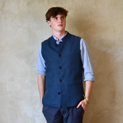 Navy Linen Slim Cut Gilet. A bespoke Pure Irish Linen waistcoat, handmade in London. Lined in pure cotton ticking with a Nehru collar. Worn buttoned over a blue shirt, Full length view.