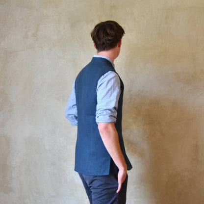 Navy Linen Slim Cut Gilet. A bespoke Pure Irish Linen waistcoat, handmade in London. Lined in pure cotton ticking with a Nehru collar. Side on Rear view worn over a blue shirt, Full length view.