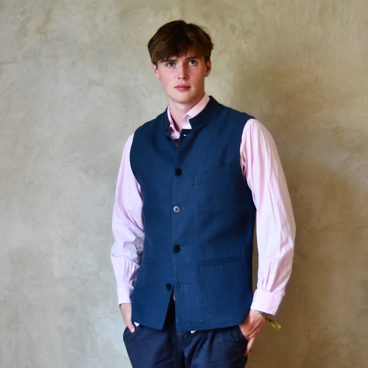 Navy Linen Slim Cut Gilet. A bespoke Pure Irish Linen waistcoat, handmade in London. Lined in pure cotton ticking with a Nehru collar. Worn closed a pink shirt, Full length view.