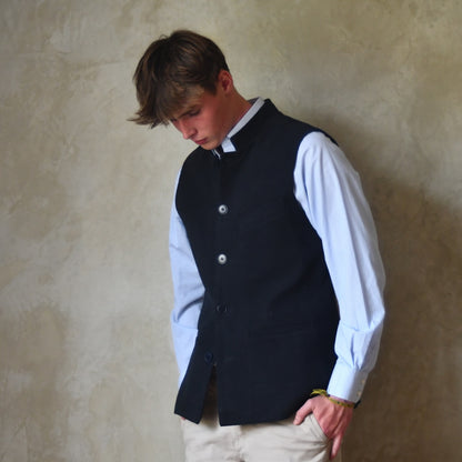 Nehru style gilet in navy moleskin. A bespoke slim-fit gilet in a pure cotton navy moleskin fabric handmade for you in London. A side view sworn half open over blue shirt.