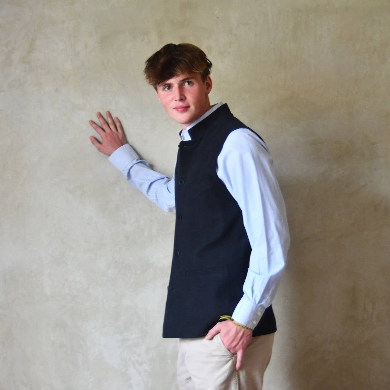 Side view of Nehru style gilet in navy moleskin. A bespoke slim-fit gilet in a pure cotton navy moleskin fabric handmade for you in London. Shown worn closed over blue shirt.